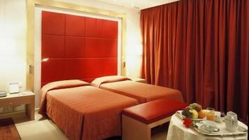 A hotel room with two beds, a small table with breakfast, and a red curtain.