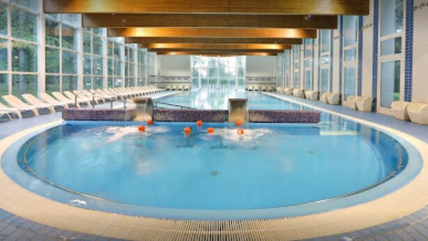 A large indoor swimming pool with clear blue water, surrounded by lounge chairs and a tiled floor. - Hotel delle Rose Terme & Wellnes Spa (Montechiarugolo)