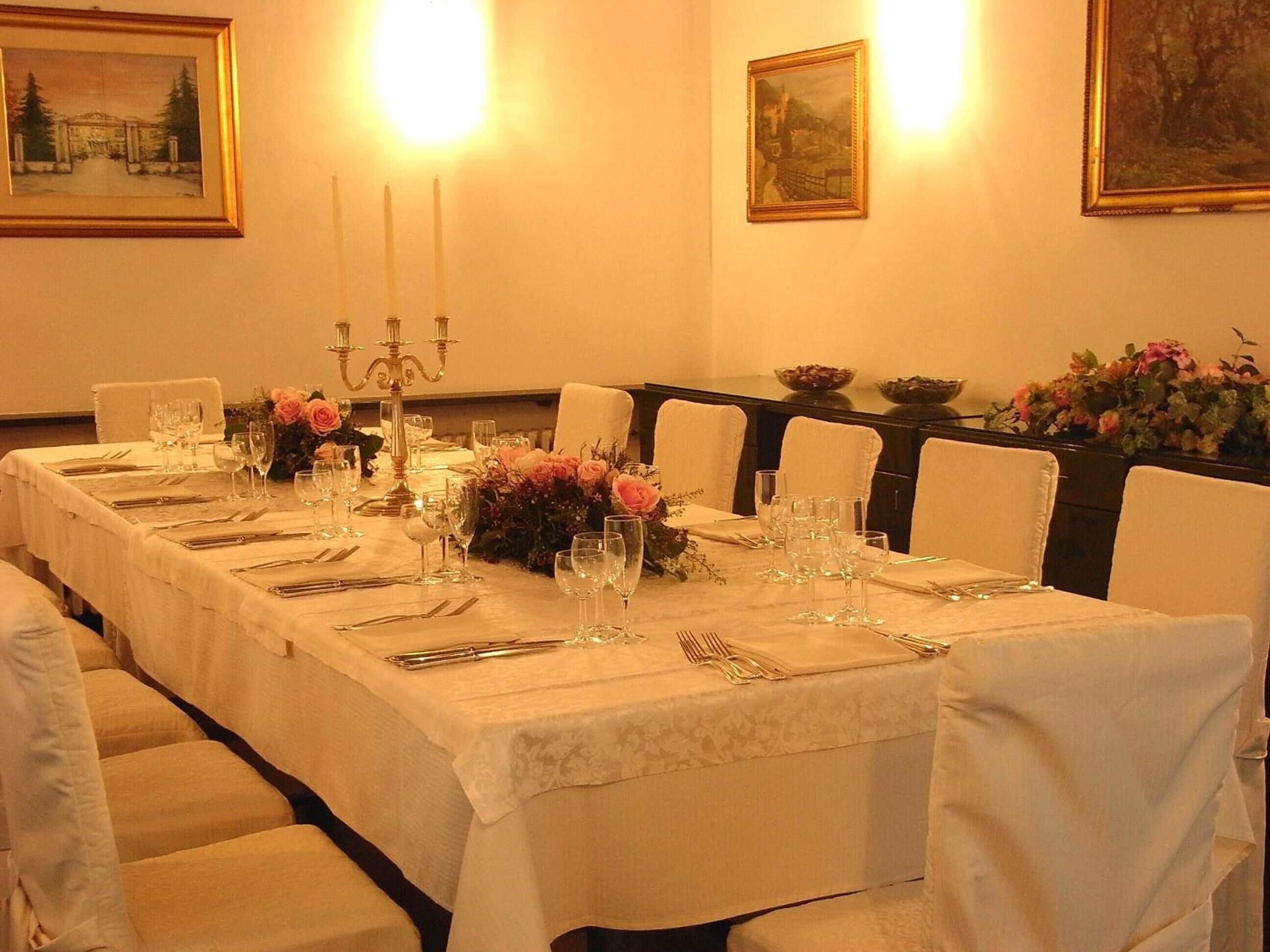 A formal dining room with a long table set for a meal, surrounded by chairs.