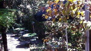An outdoor patio area with tables and chairs, surrounded by dense foliage and trees. - Hotel Aspromonte (Milan)