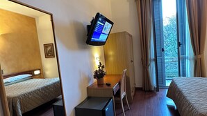 A hotel room with a bed, a desk with a computer, a chair, a small table with a plant, and a window with curtains. - Hotel Aspromonte (Milan)