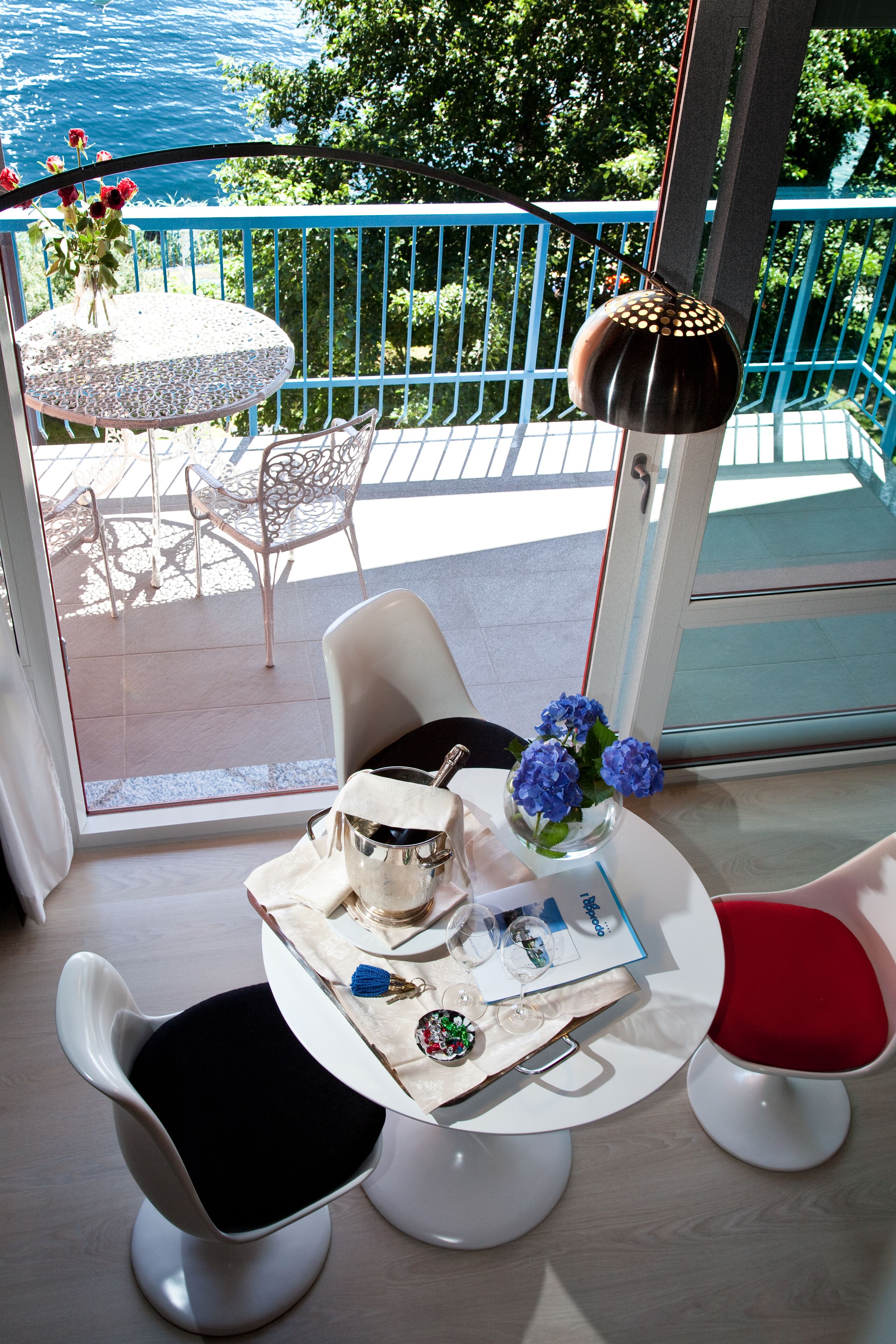 A balcony with a table, chairs, and a vase of flowers.