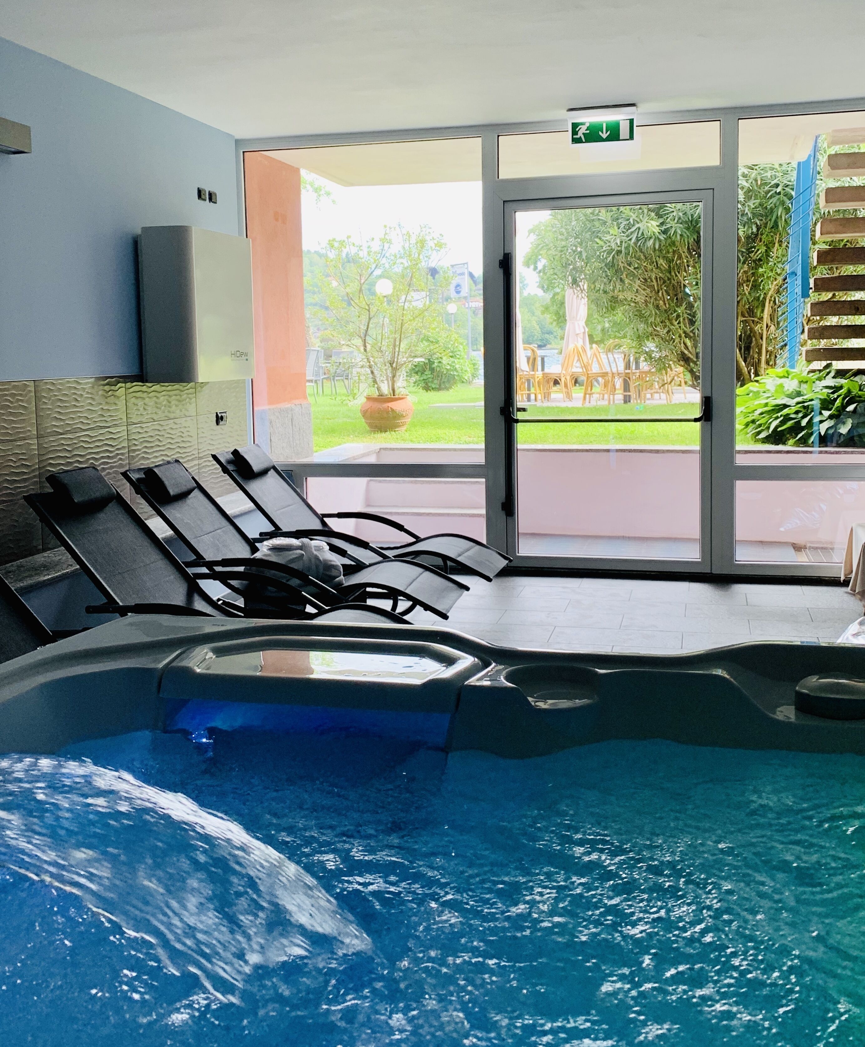 Zona de piscina con sillones de descanso y puerta de cristal que da al exterior.
