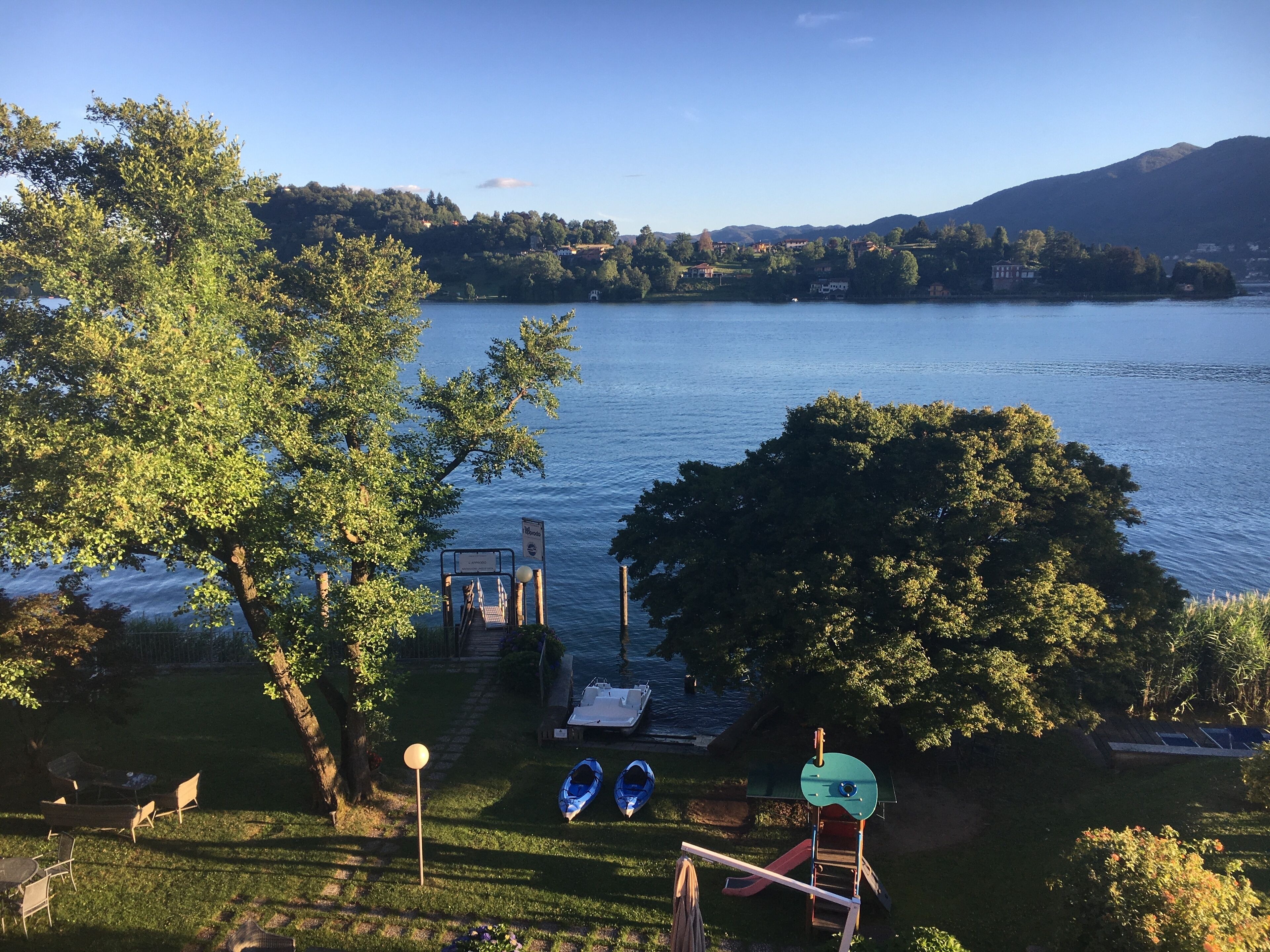 A lakeside view with a gazebo, two kayaks, and a small boat dock.