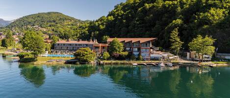Un hotel junto al lago con varias construcciones, una piscina y barcos amarrados en el muelle.