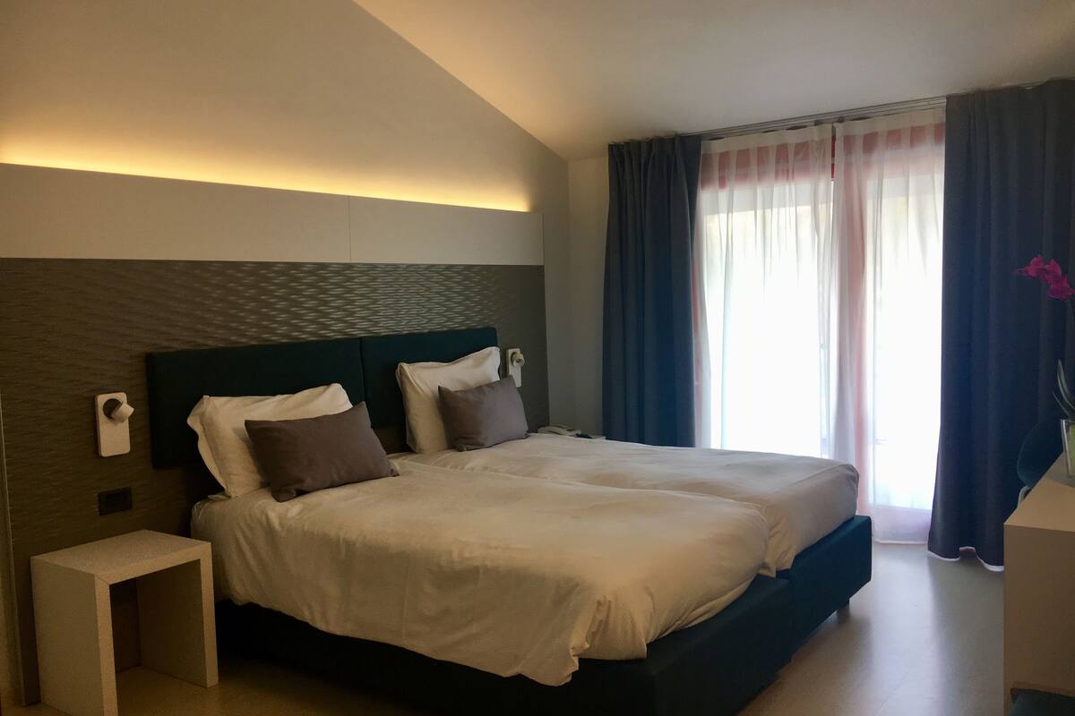 Une chambre d’hôtel moderne avec un grand lit, une table de chevet et une petite table de nuit.