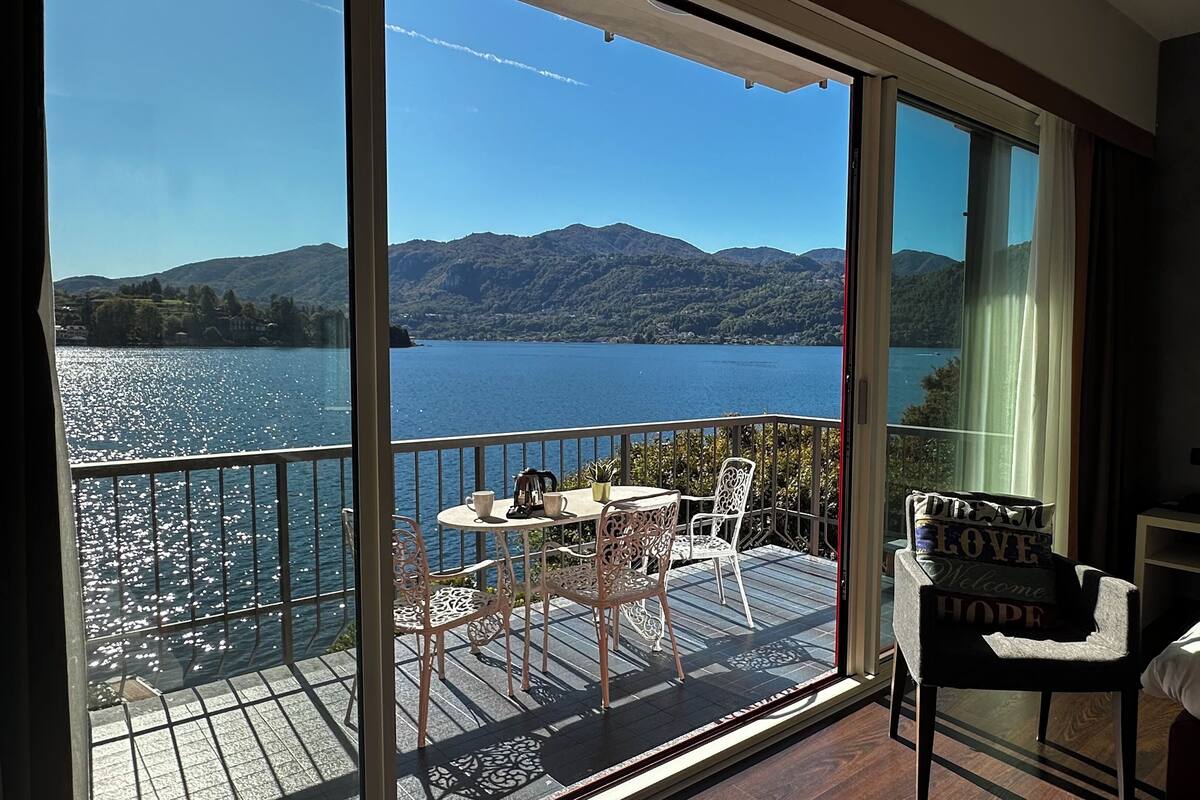 Un balcon avec une table et des chaises donnant sur un lac et des montagnes.