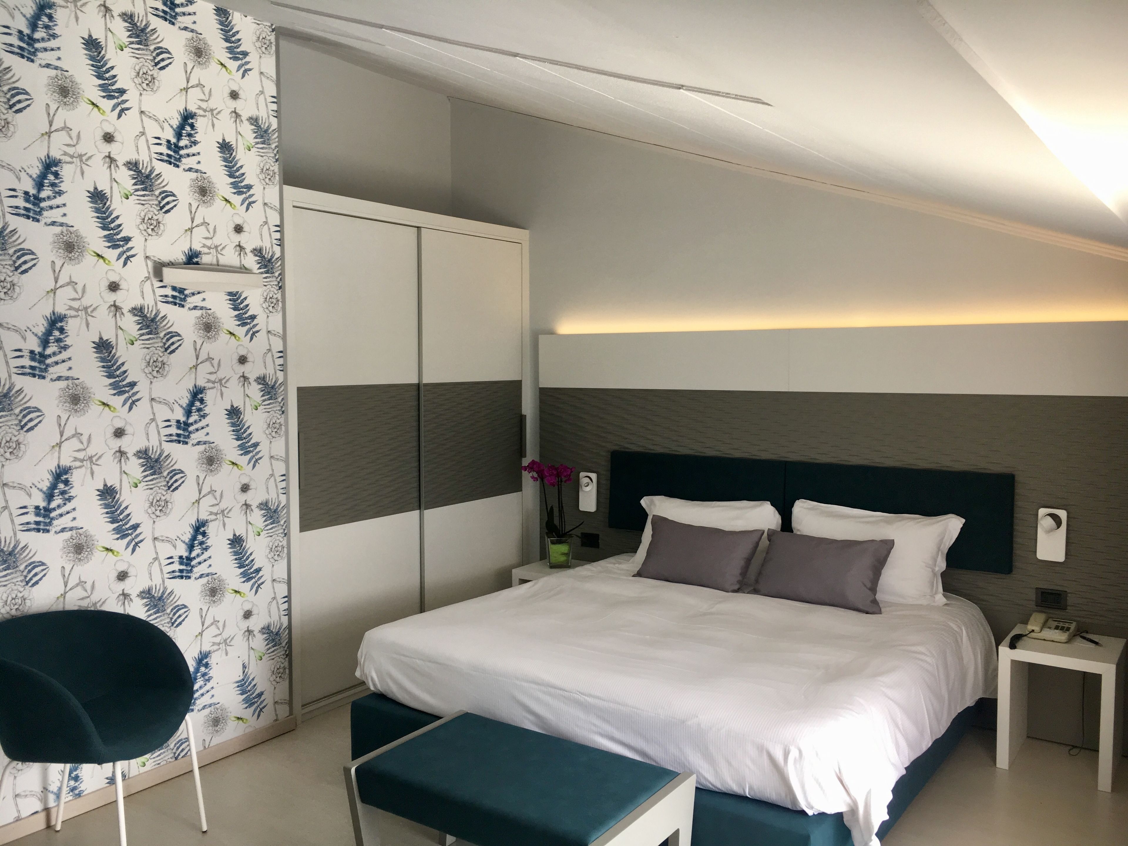 Ein modernes Schlafzimmer mit Bett, Nachttischen, einem Sessel und einem Kleiderschrank.