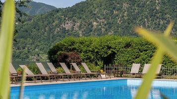 Ein Pool mit Liegestühlen und einem Berg im Hintergrund.