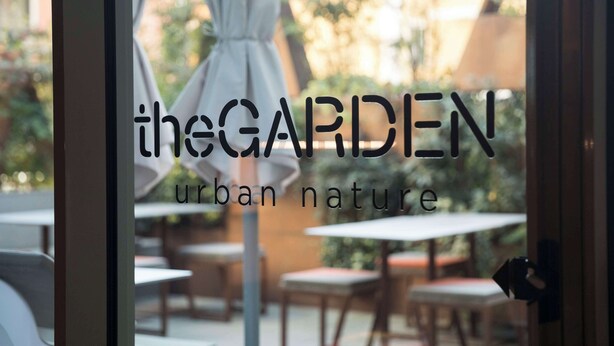 Un letrero con el texto 'the GARDEN urban nature' en un café.
