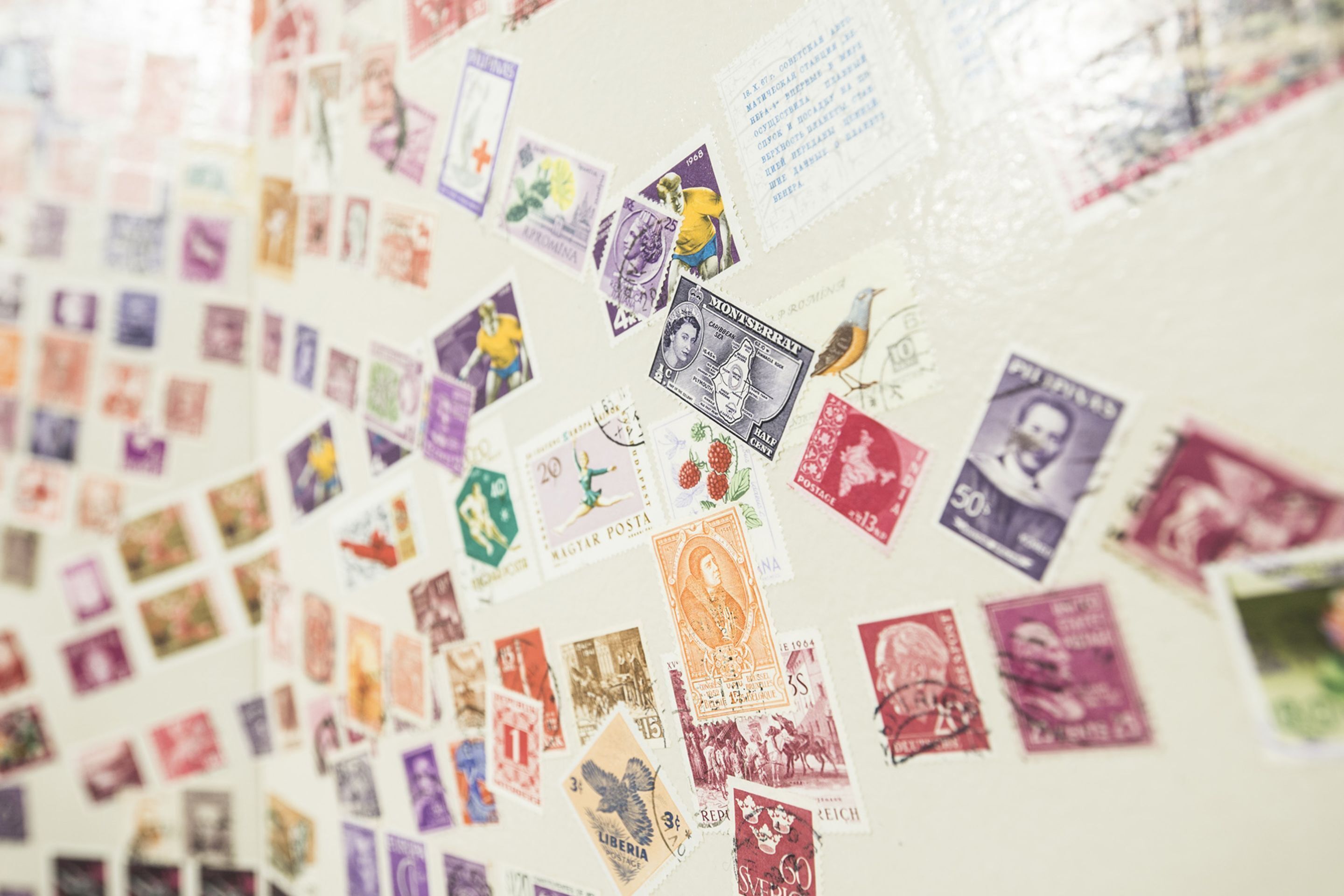 A wall covered with various stamps and postcards.