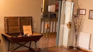 Quarto com mesa de madeira, armário de vidro e vaso com galhos.