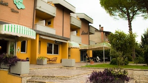 Um hotel com fachada amarela, área de estar ao ar livre e um jardim.