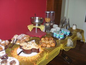 Uma mesa de buffet com diversos alimentos, incluindo doces, bolo e laticínios.