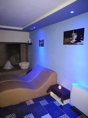 Um spa moderno com área de estar curvo, uma mesinha com velas e um aquecedor fixado na parede.
