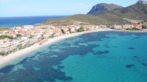 Une ville côtière avec des bâtiments qui bordent la plage et une eau d’un bleu limpide.