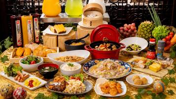 A variety of dishes and food items on a table, including a red pot, bowls of soup, and plates of food.