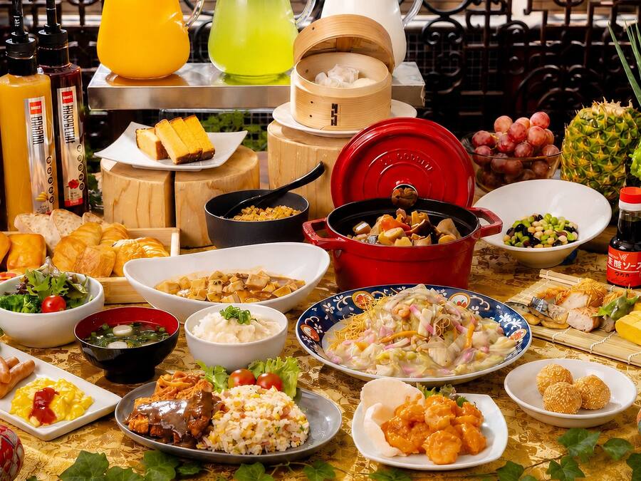 A variety of dishes and food items on a table, including a red pot, bowls of soup, and plates of food.