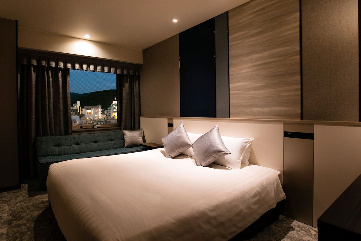 Ett modernt hotellrum med en stor säng, en sittgrupp och utsikt över staden.