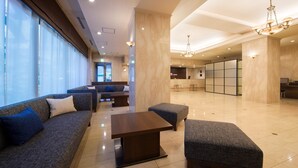 Un amplio vestíbulo con un sofá, un reposapiés y una mesa.
