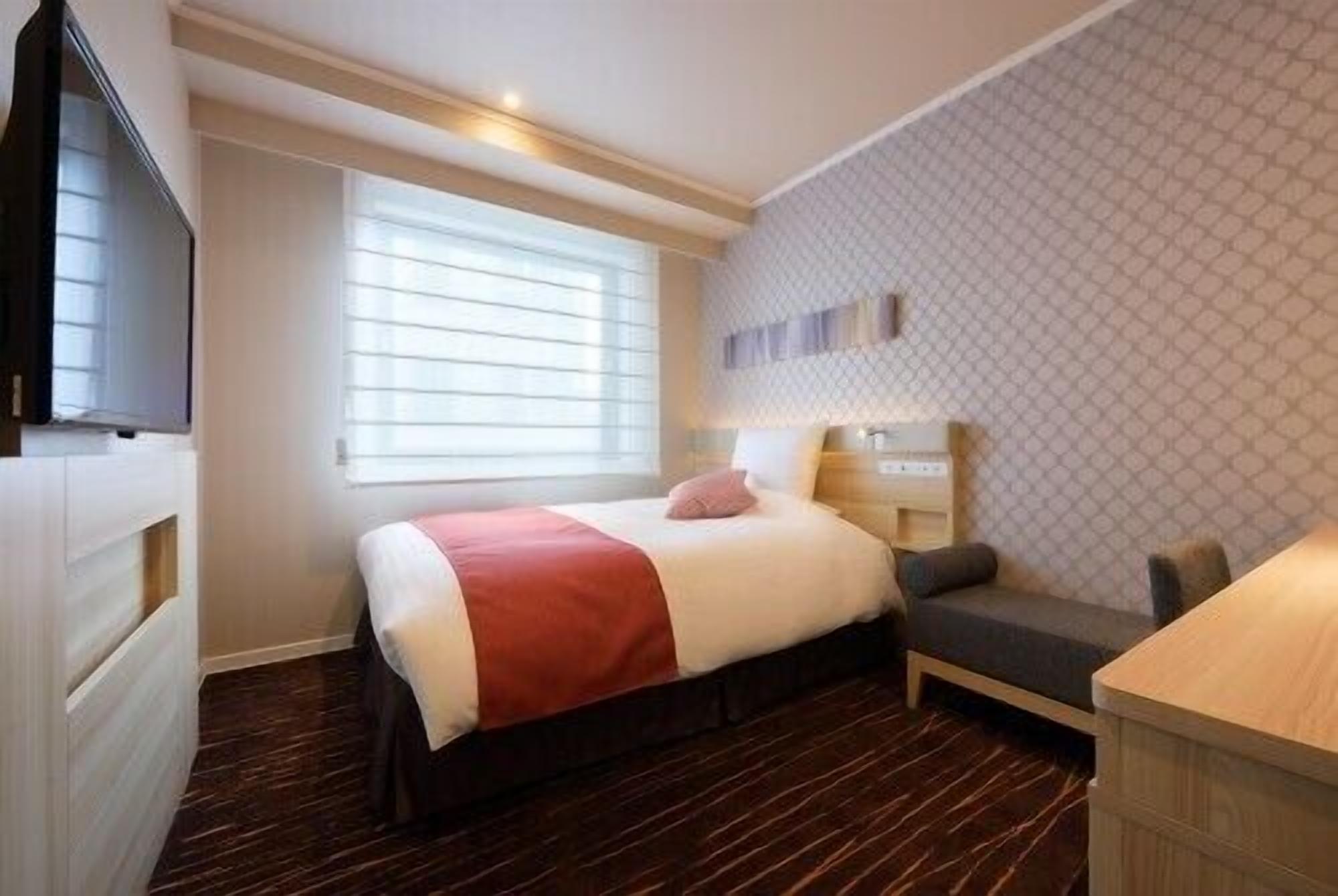A hotel room with a bed, bedside table, and a TV.