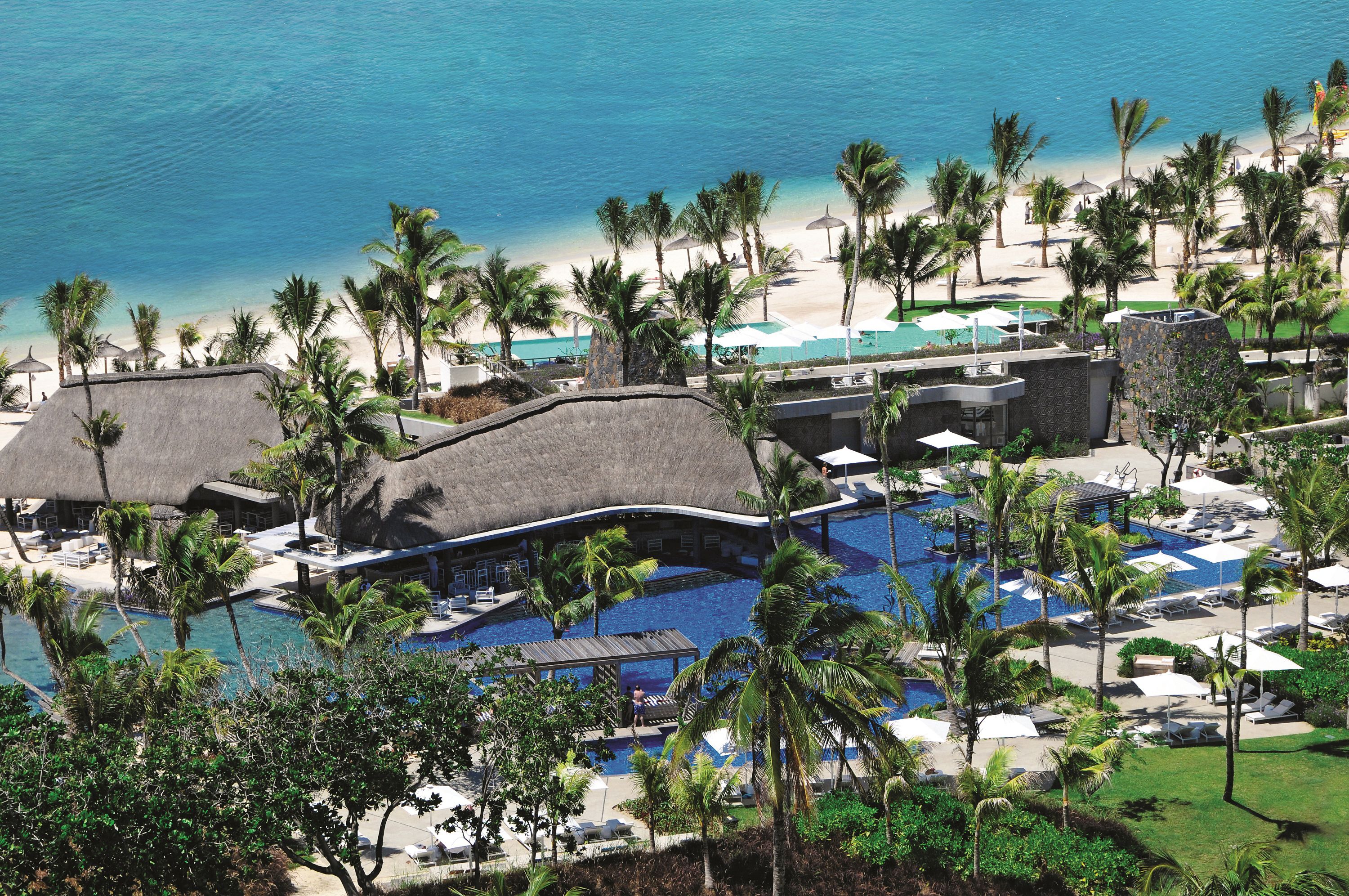 Un complexe hôtelier doté d’une grande piscine, d’une plage et de palmiers.