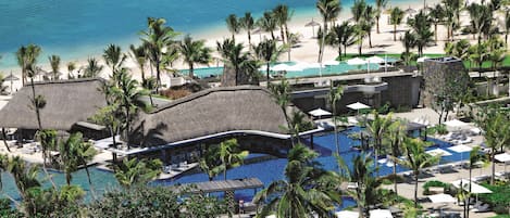 Un resort con una piscina grande, playa y palmeras.