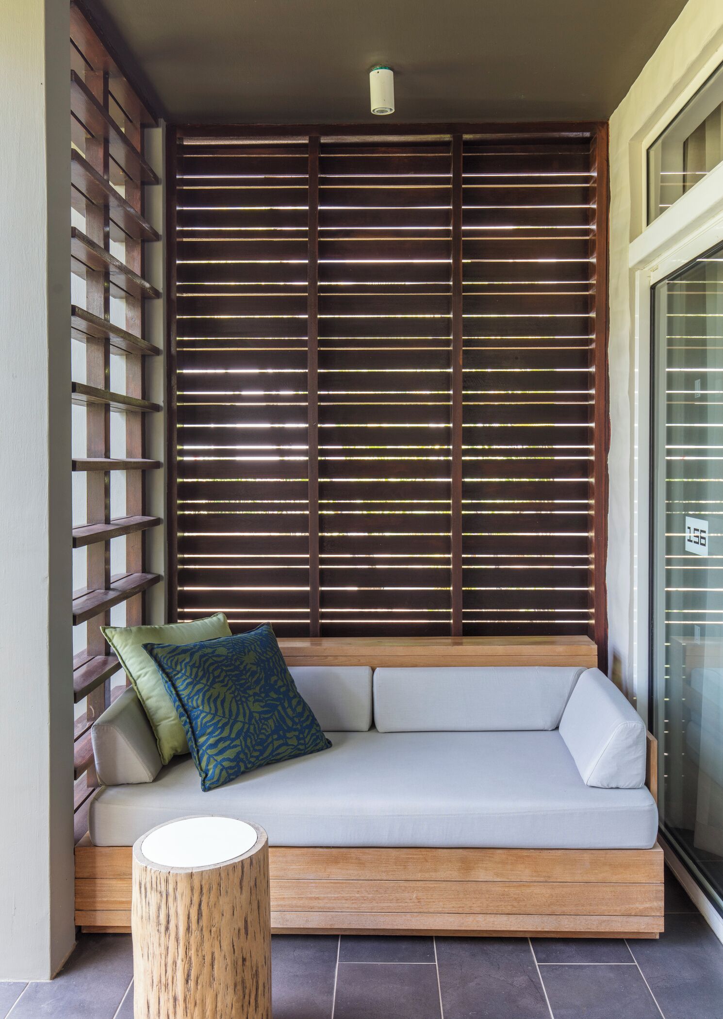 Een moderne buitenruimte met een houten bank, een comfortabele loungebank en een houten kruk.