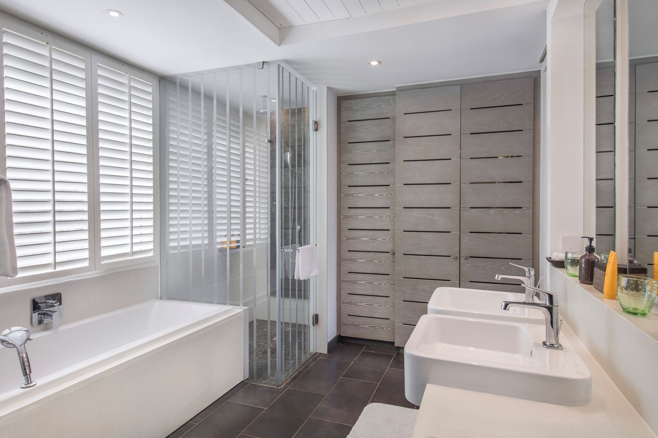 Een moderne badkamer met een douchecabine, een ruime badkuip en twee wastafels.