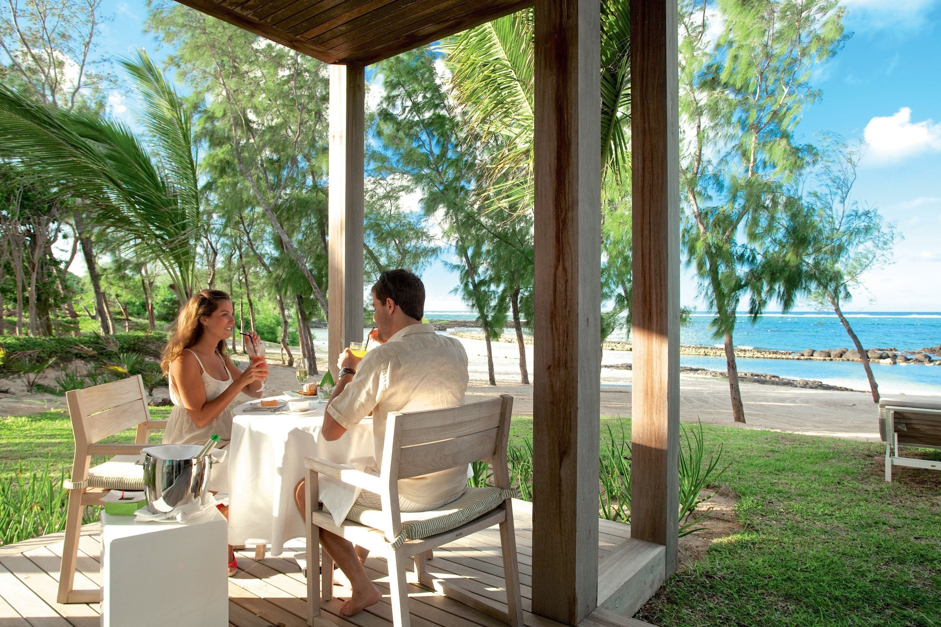 A covered outdoor dining area with a view of the beach and ocean.