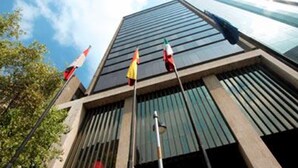 Un bâtiment moderne doté d’une façade en verre et de plusieurs drapeaux flottant sur des mâts.