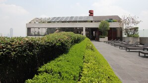 Une terrasse sur le toit, avec un bâtiment moderne, des panneaux solaires et des chaises longues.
