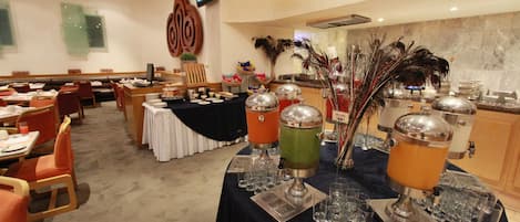 A buffet setup with multiple drink dispensers and a variety of food items on tables.