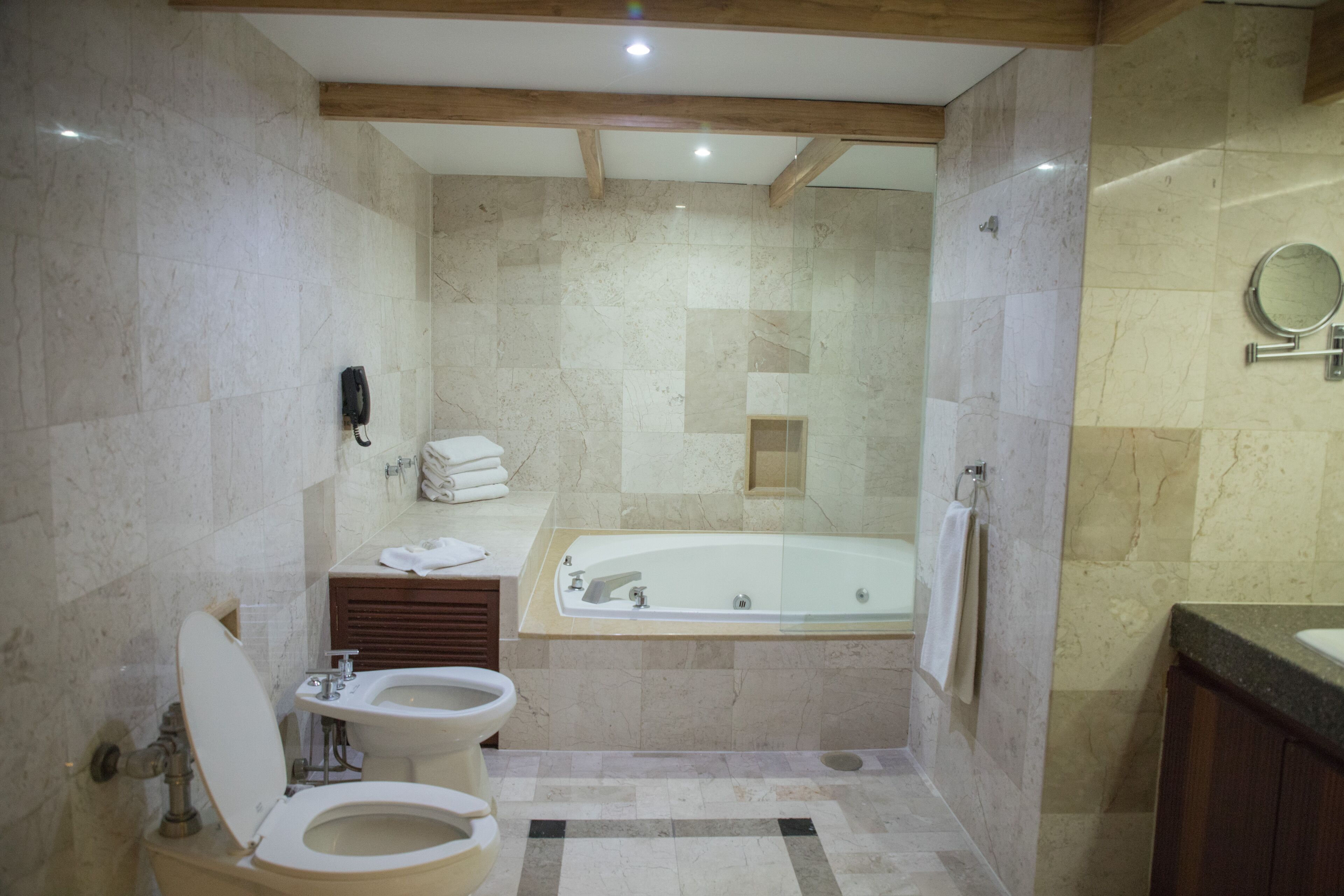 A modern bathroom with a toilet, bidet, sink, vanity, and a large bathtub.