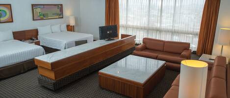Habitación de hotel con dos camas, un sofá, un escritorio y un televisor.