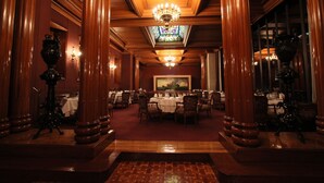 Une salle à manger élégante, avec des colonnes en bois, des lustres et une fenêtre à vitraux.