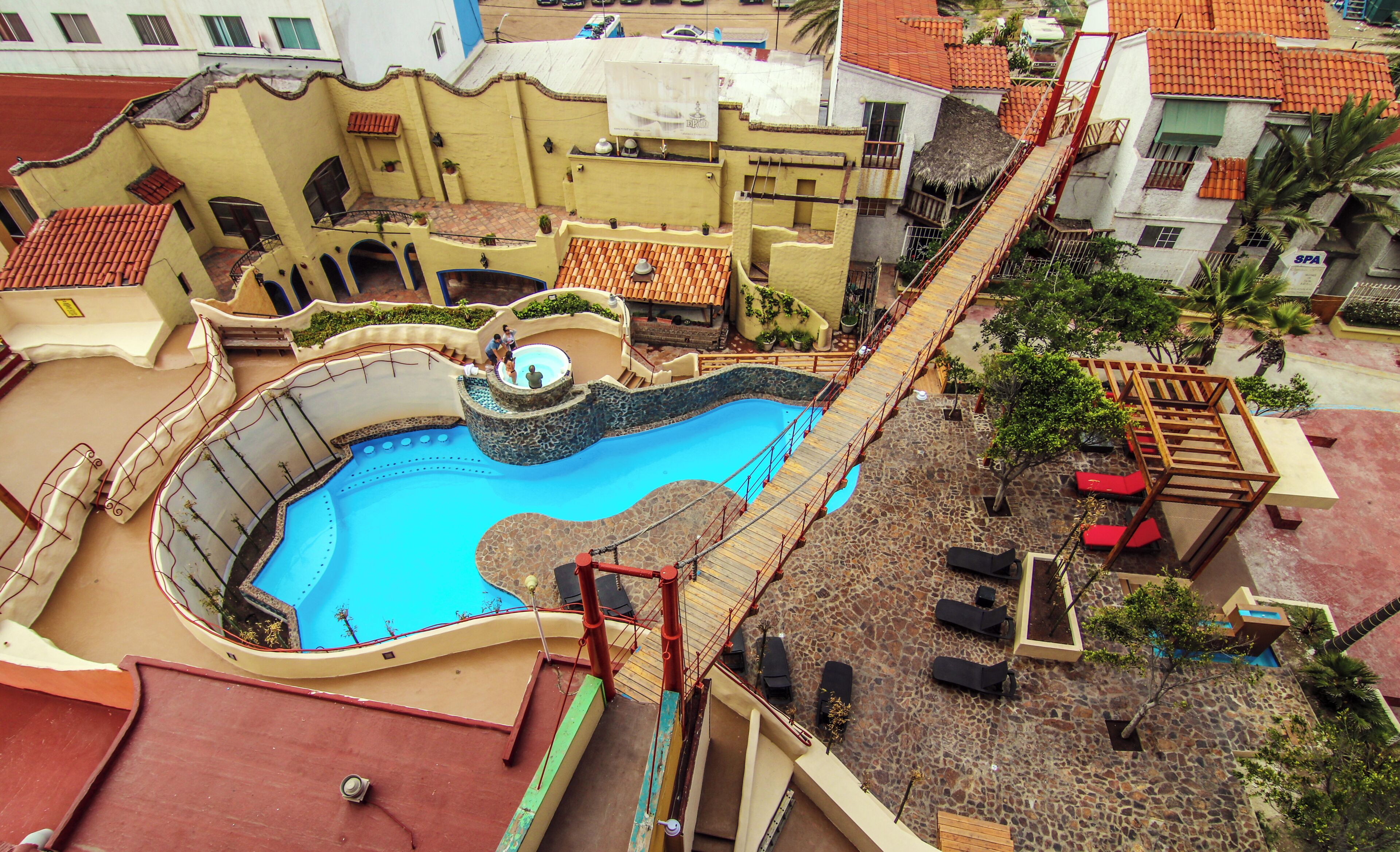 Piscina con tobogán, mobiliario exterior y una escalera que lleva a una terraza.