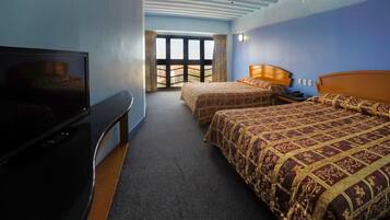 Une chambre d’hôtel avec deux lits, une télévision, un ventilateur de plafond et une grande fenêtre.