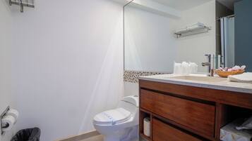 A bathroom with a toilet, a sink with a mirror, a towel rack, and a trash bin.
