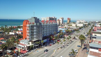 A hotel with a modern facade, located near a busy street and a beach.