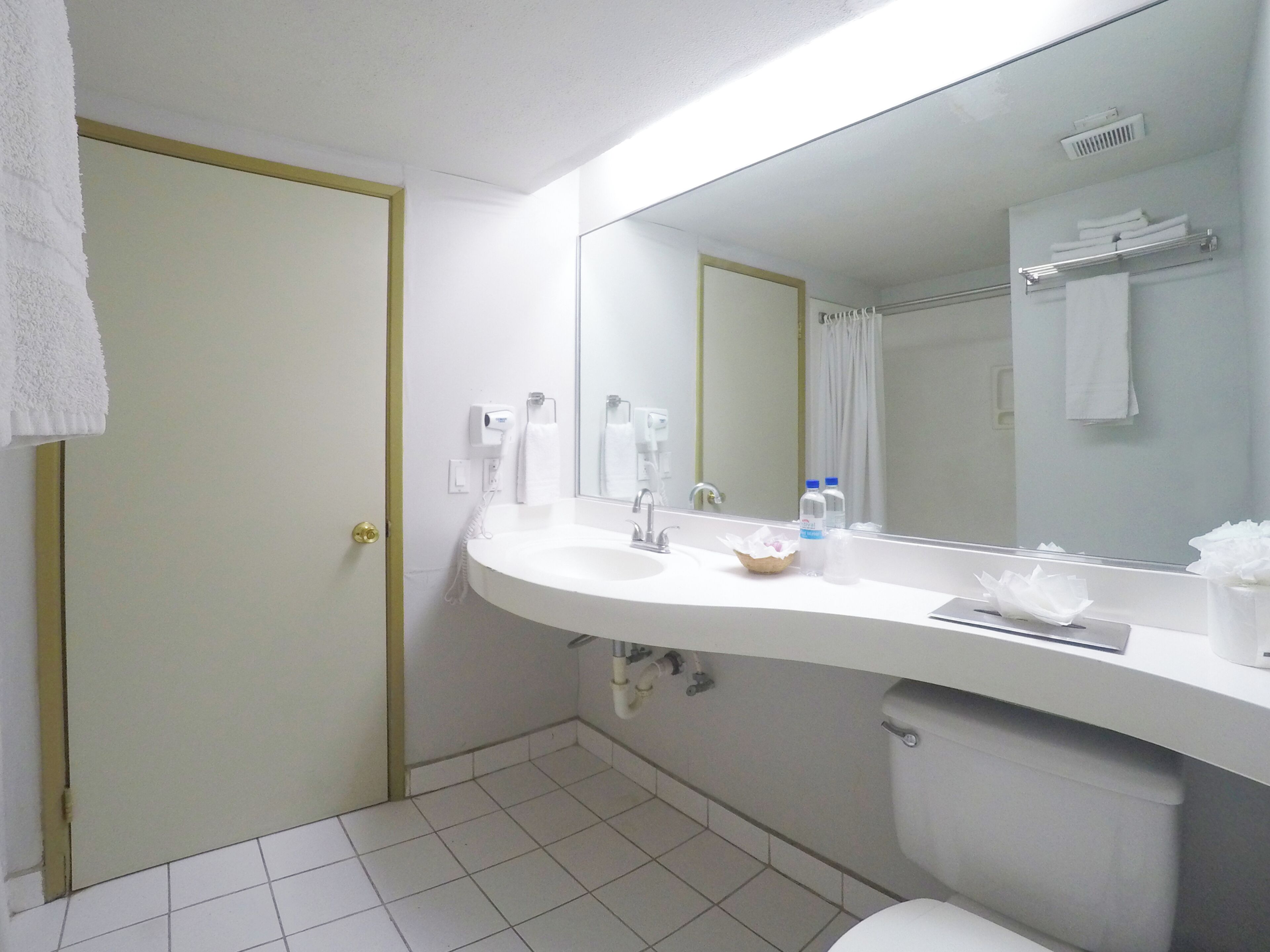 A bathroom with a white sink, a mirror, a toilet, and a shower curtain.