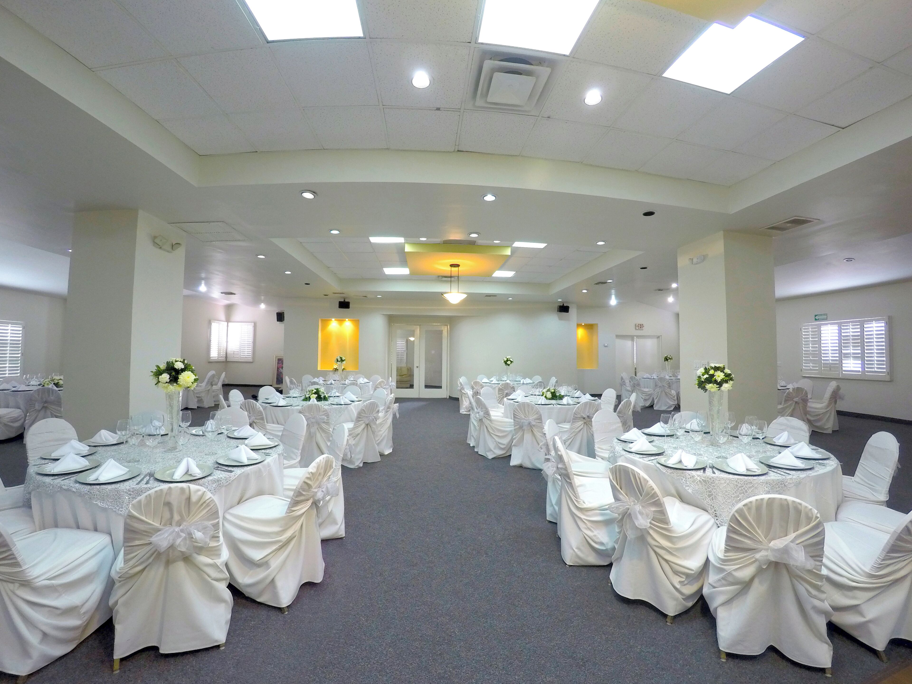 A conference room with round tables, white chairs, and a carpeted floor.