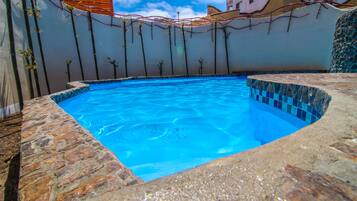 Alberca al aire libre, sombrillas en la alberca y camastros