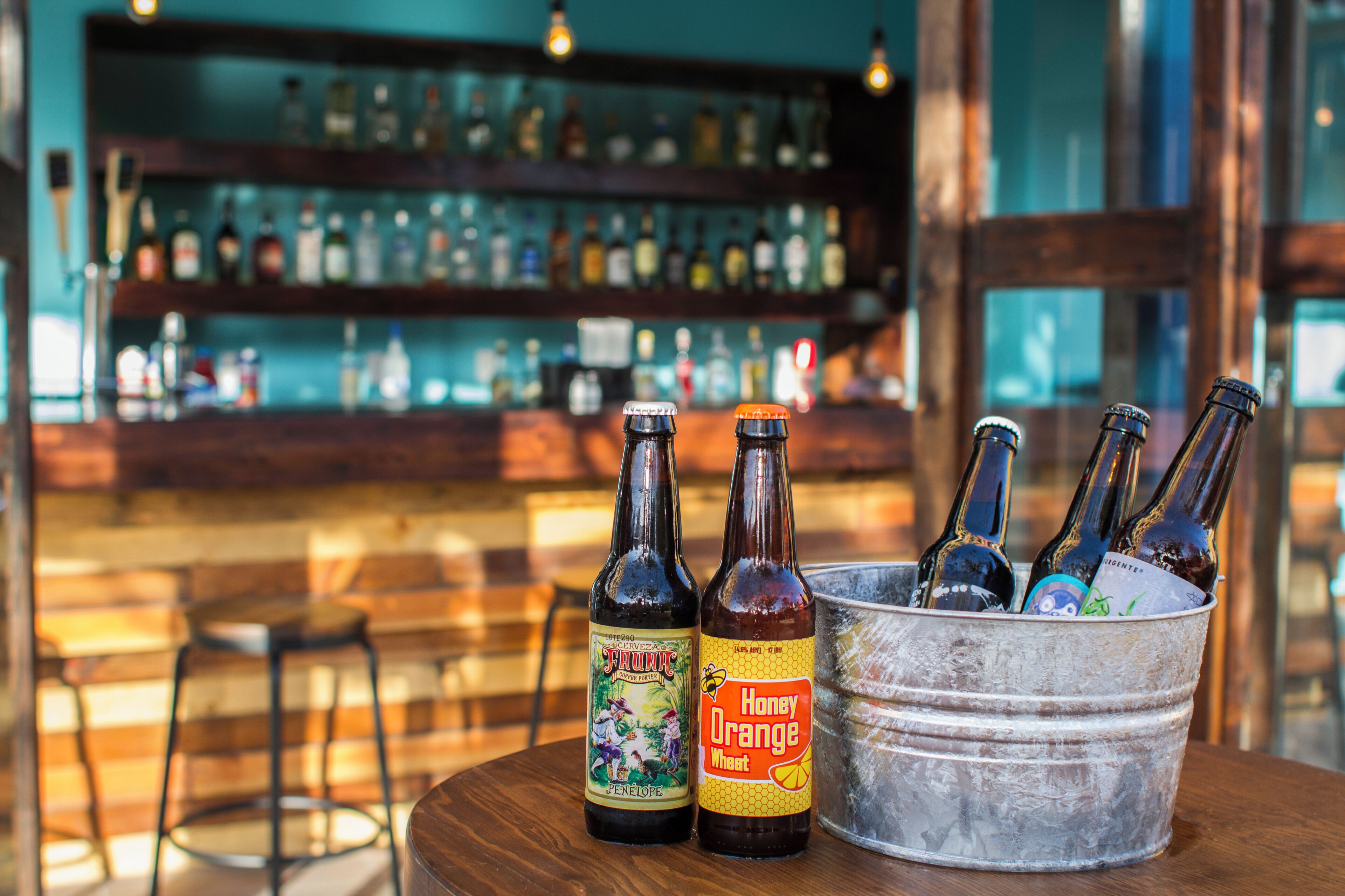 A bar setting with bottles in a bucket and a shelf with various bottles in the background.