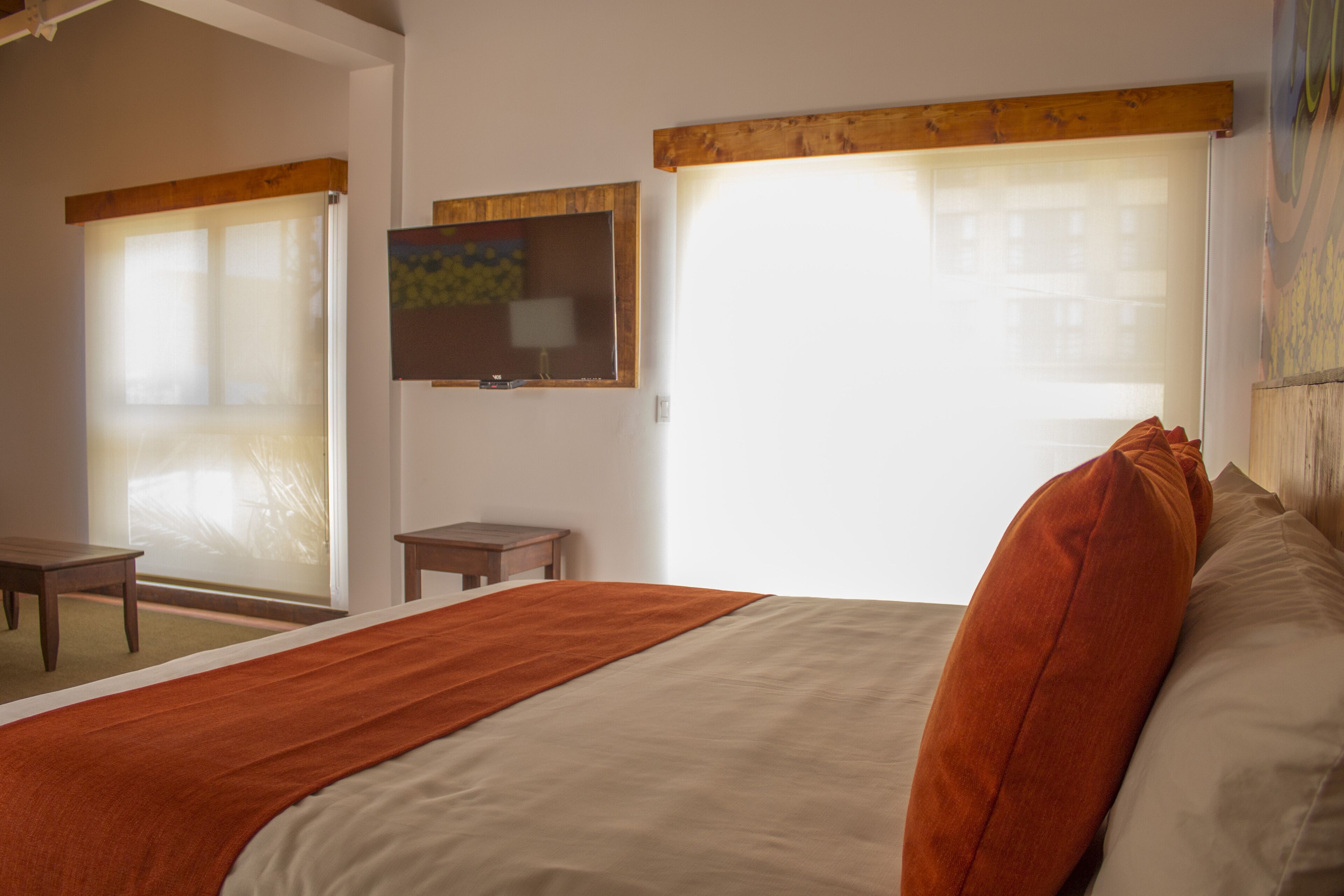 Habitación de hotel con cama, una mesita, televisor y ventana con persianas.