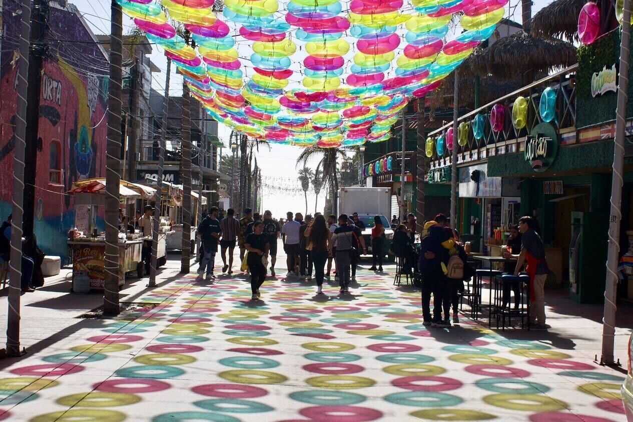 Una calle con llamativos diseños circulares en el pavimento, tiendas a ambos lados y una multitud de gente.
