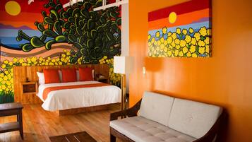 Quarto com uma cama, um sofá, uma mesa de cabeceira de madeira e um mural na parede.