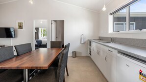 A modern kitchen with white cabinets, a granite countertop, and a built-in dishwasher. - Lake Lodge Motel (Rotorua)
