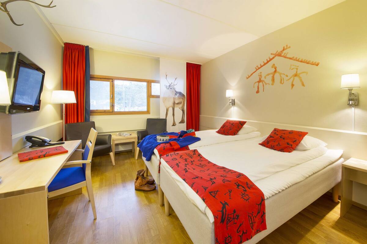 A hotel room with a bed, desk, chair, TV, and a window.