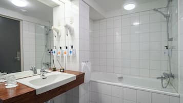 A modern bathroom with a dual sink vanity, a large mirror, a shower with a handheld showerhead, and a bathtub.